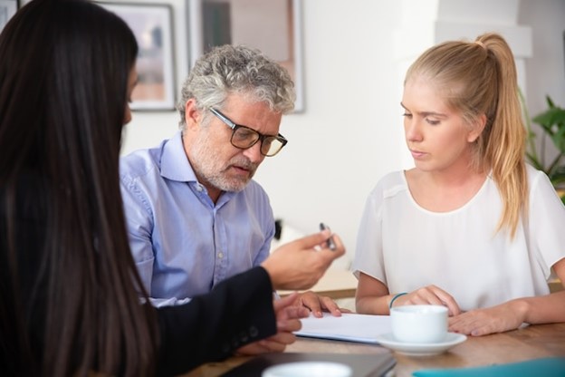 focused-mature-man-reading-document-his-female-colleague-giving-pen-him-signing